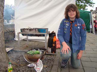 Boy Scout cooking Sea Trout wrapped in cabbage leaf on a BBQ